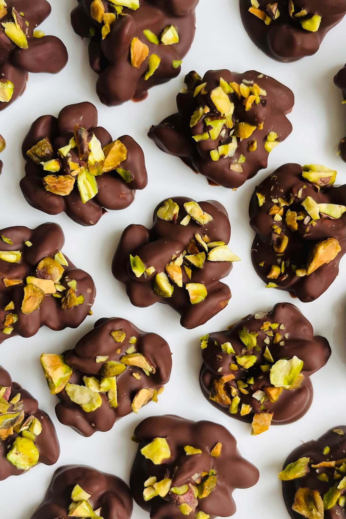 Chocolate covered pistachios on a white plate.