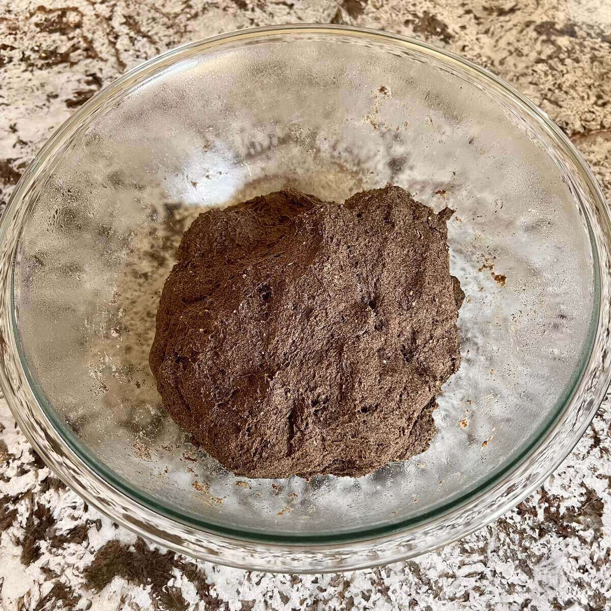 Risen bread dough in a large glass bowl.