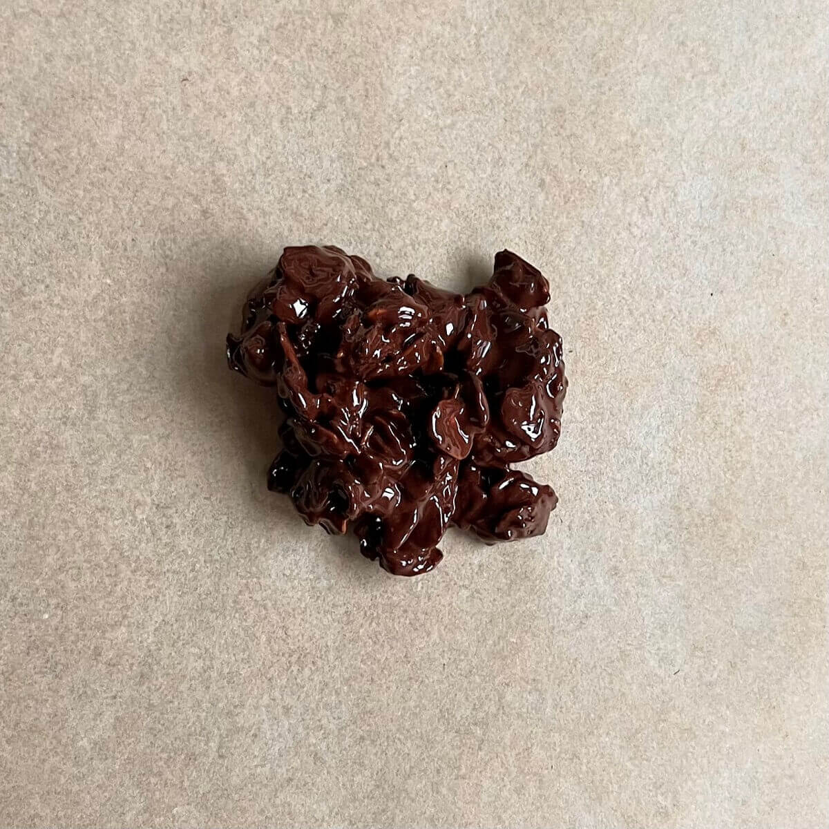 A cluster of oats and melted chocolate on parchment paper.