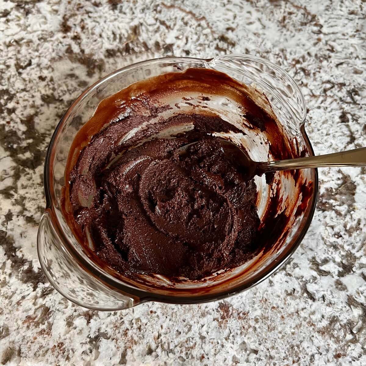 Mocha truffle filling in a glass bowl with a spoon.