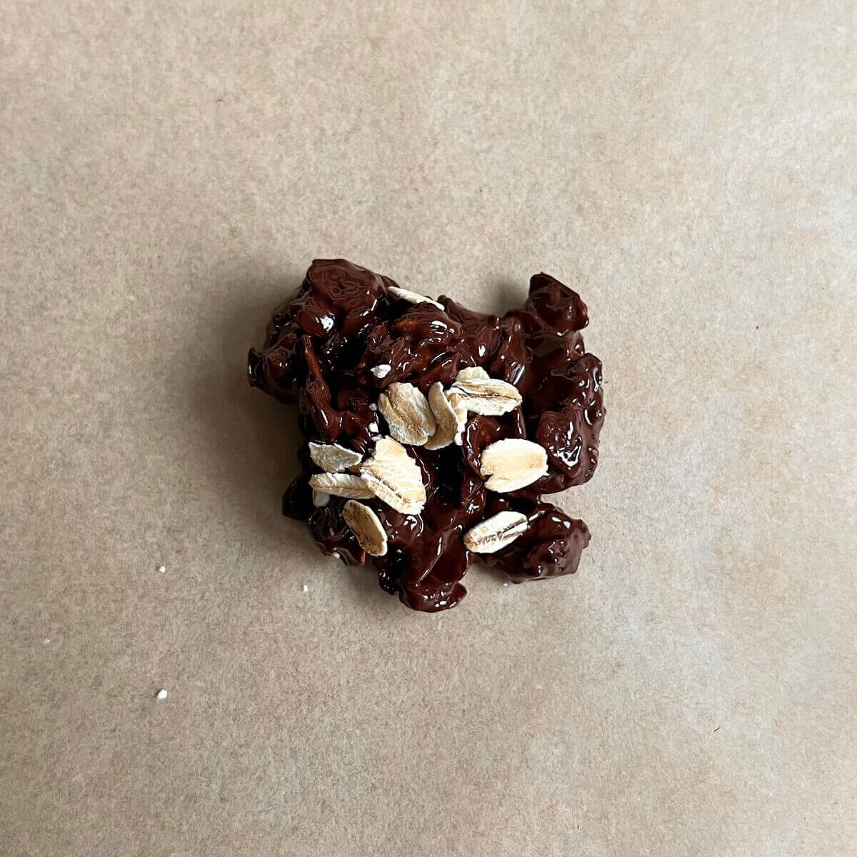 A treat made with oats and chocolate on a piece of parchment paper.