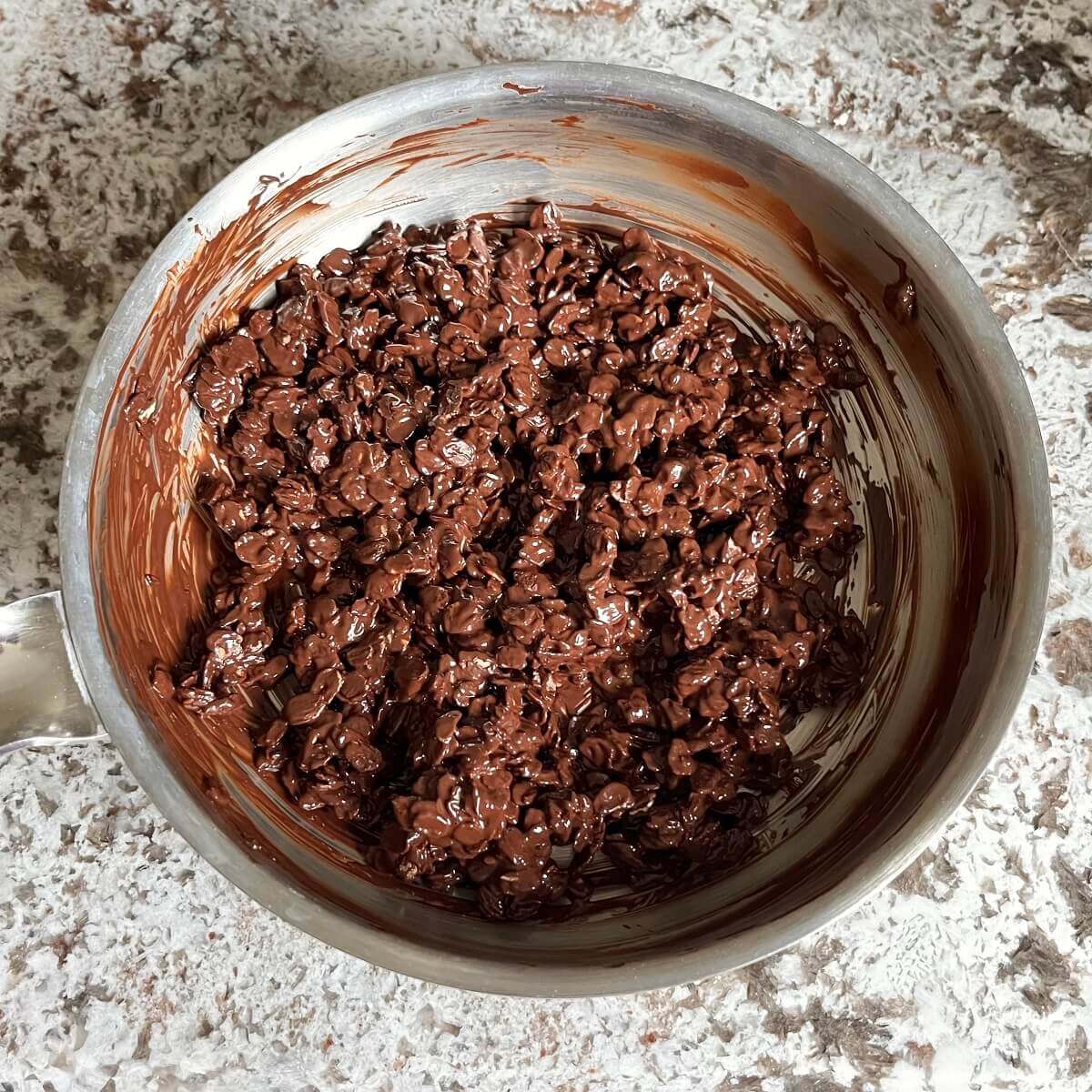 Oats covered in melted chocolate in a steel pan.