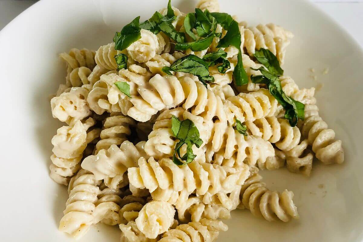 Cooked rotini pasta in a white bowl.