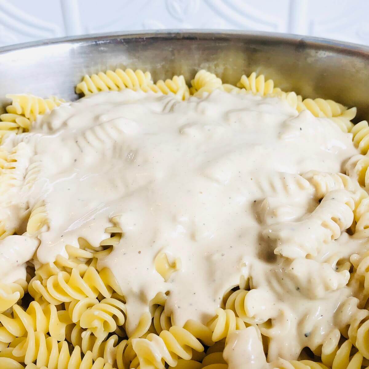 Pasta with tahini sauce in a steel bowl.