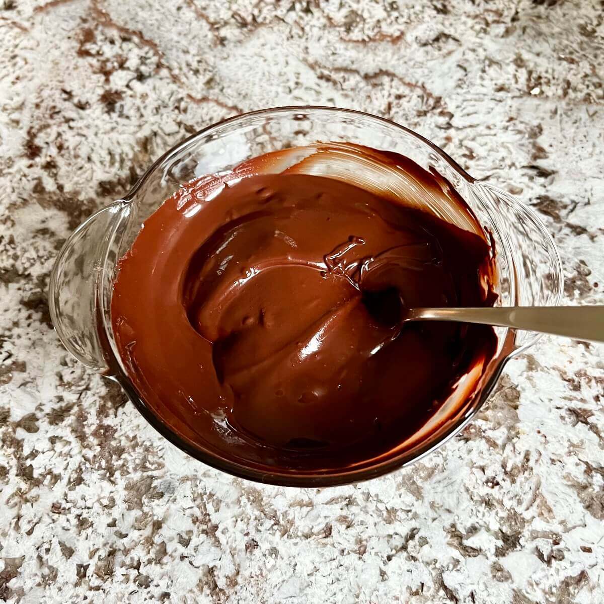 A mixture of melted chocolate and gingerbread spices in a glass bowl.
