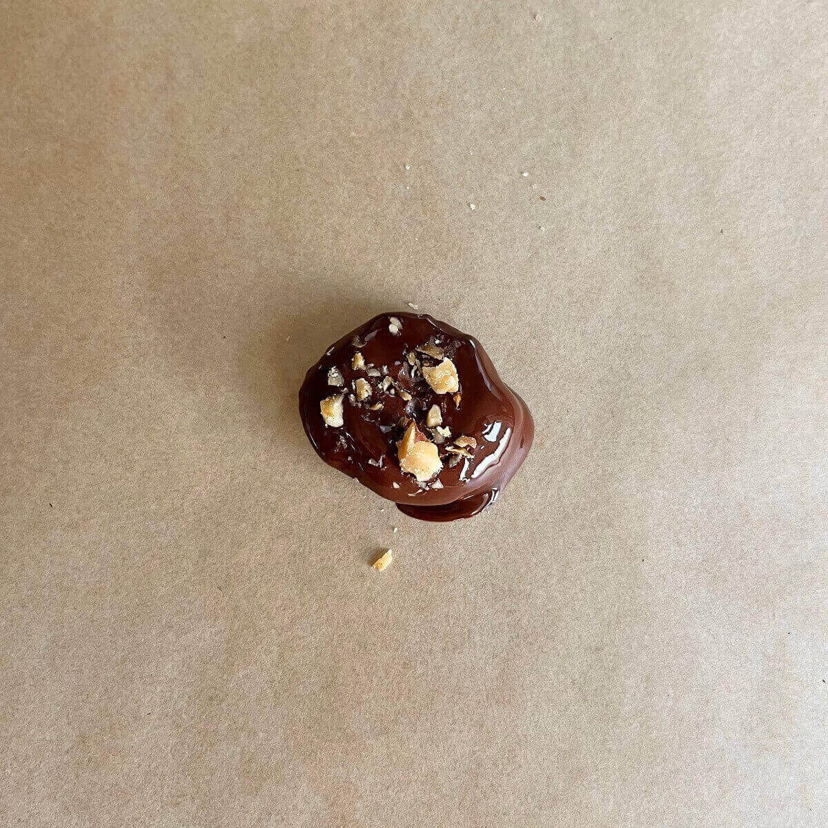 A chocolate dipped prune on parchment paper.