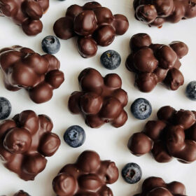 Dark chocolate covered blueberries on a white plate.