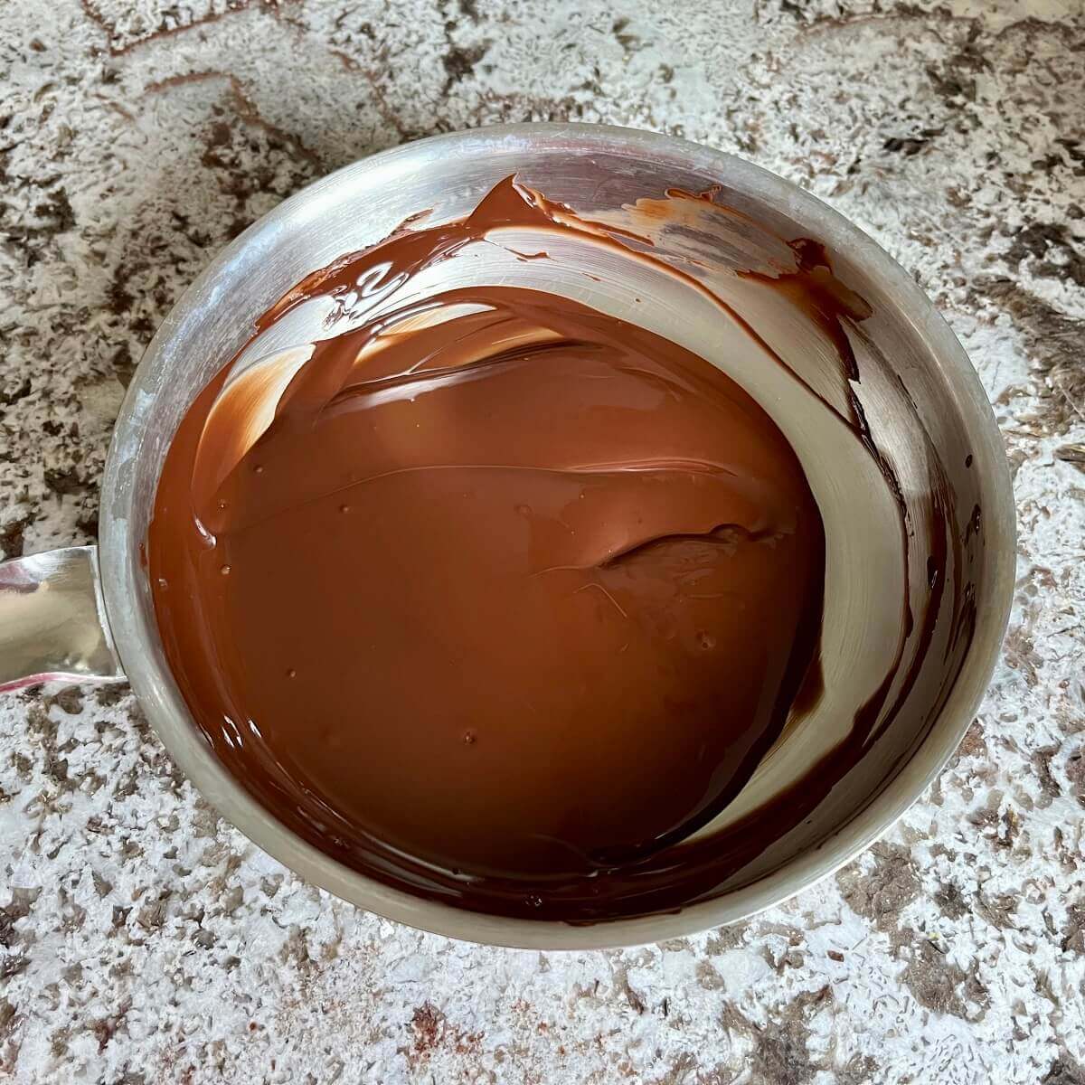 Melted dark chocolate in a steel pan.