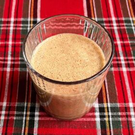 A gingerbread smoothie in a glass on a plaid placemat.