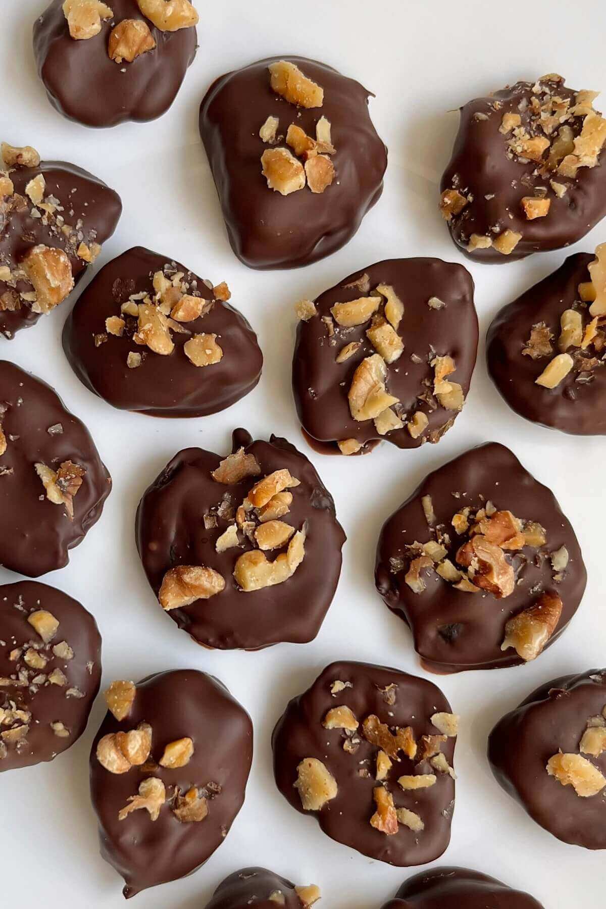 Prune chocolates on a white plate.