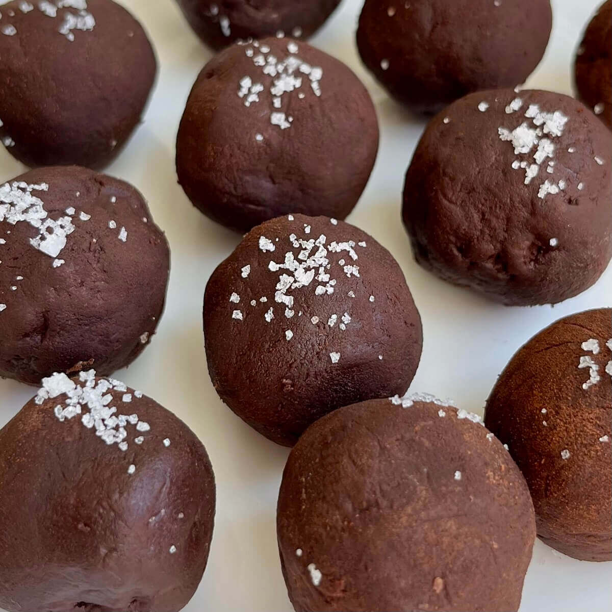 Avocado chocolates sprinkled with sea salt on a white plate.