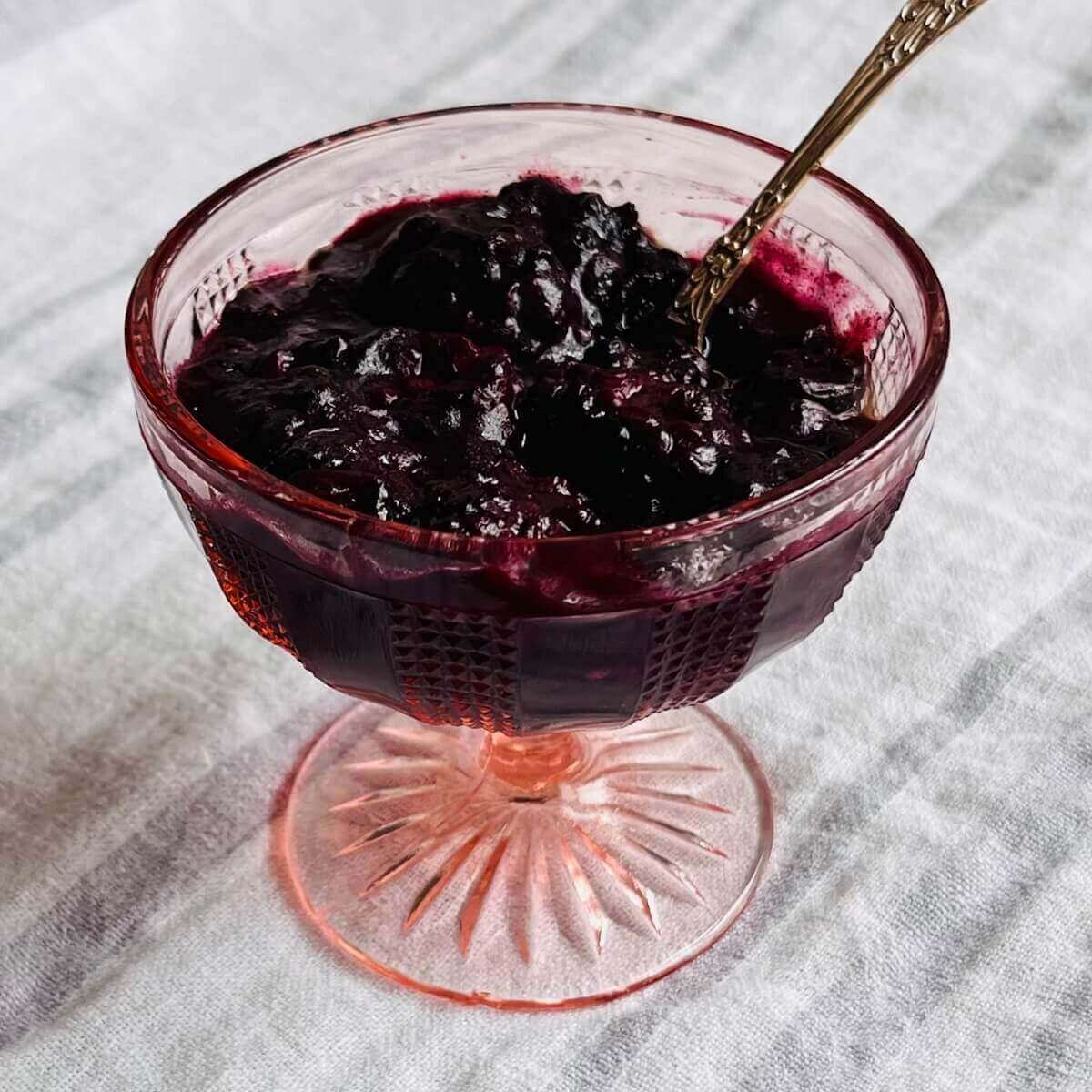 Baked berries in a vintage glass dish with an antique silver spoon.