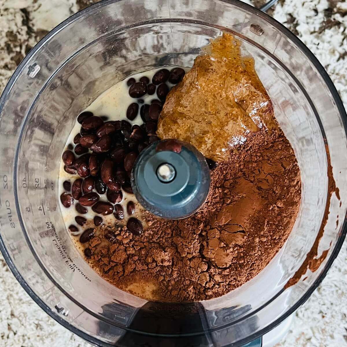 Black beans, soy milk, cocoa powder, almond butter, and vanilla extract in a food processor.