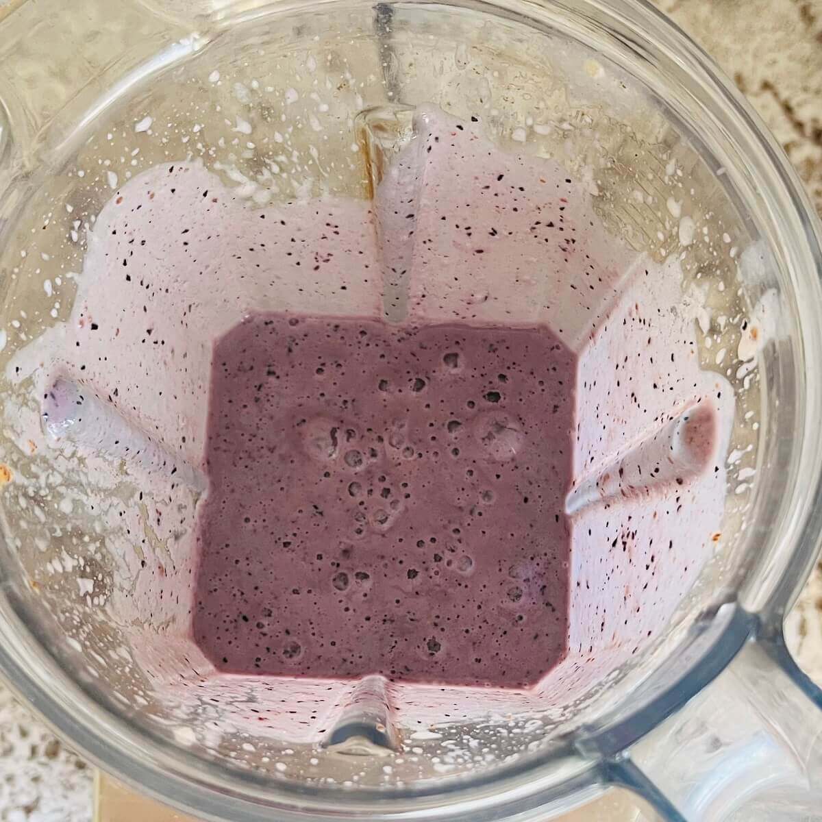 A blended blueberry smoothie in a blender.