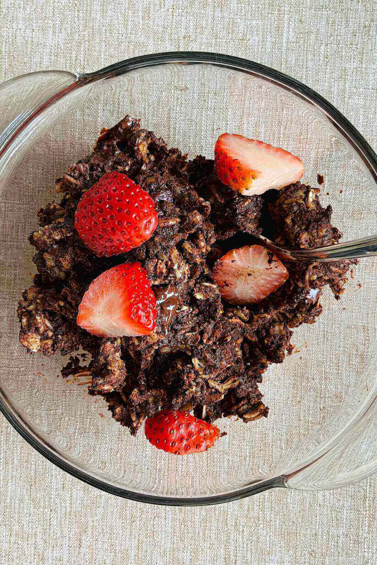 Baked brownie oatmeal sprinkled with strawberry slices in a bowl.