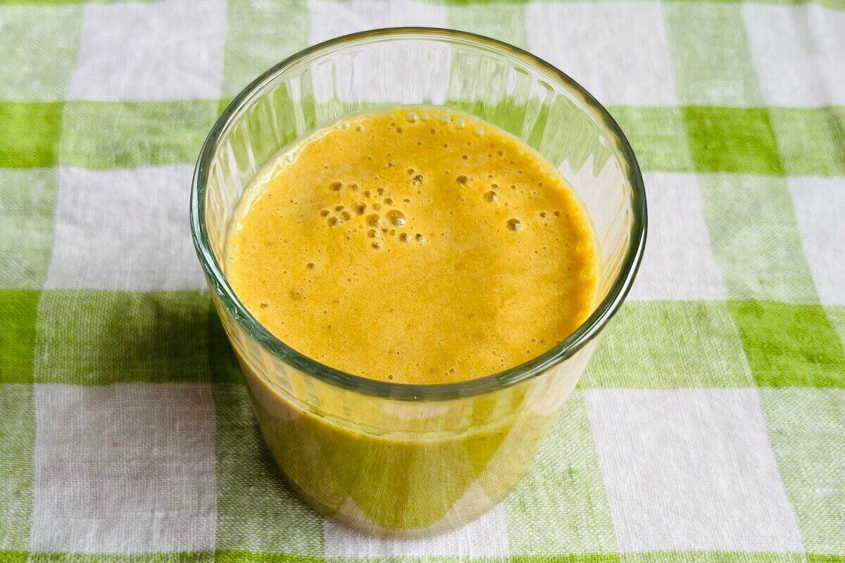 A creamy orange colored smoothie made with turmeric in a glass.