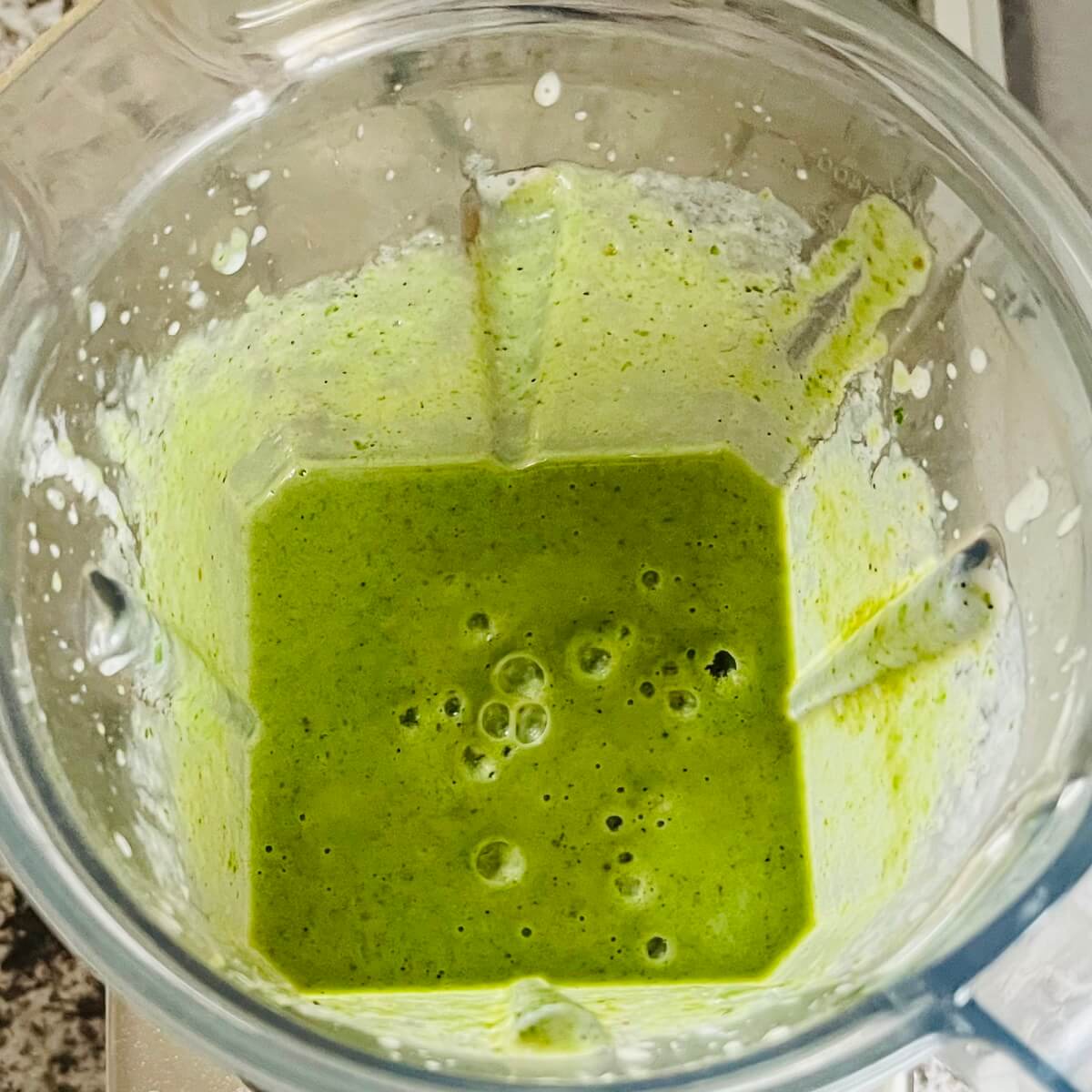 A creamy green smoothie in a blender.