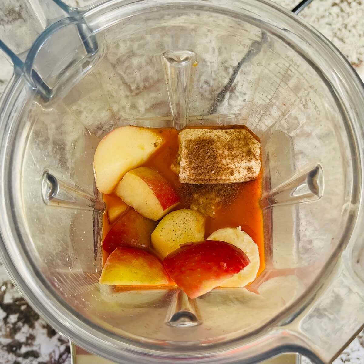 Banana, apple, carrot juice, and cinnamon in a blender.