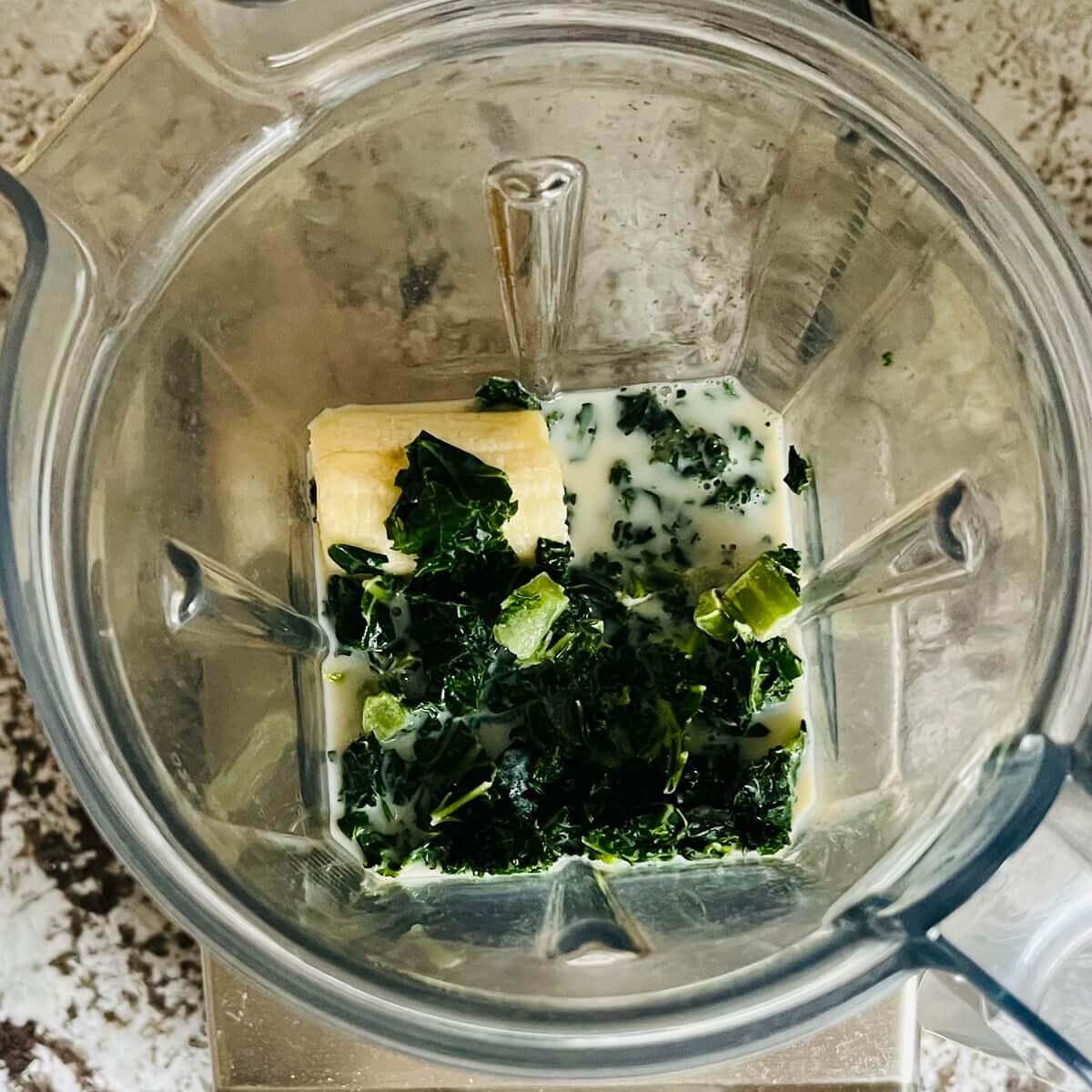 Kale and other smoothie ingredients in a blender.