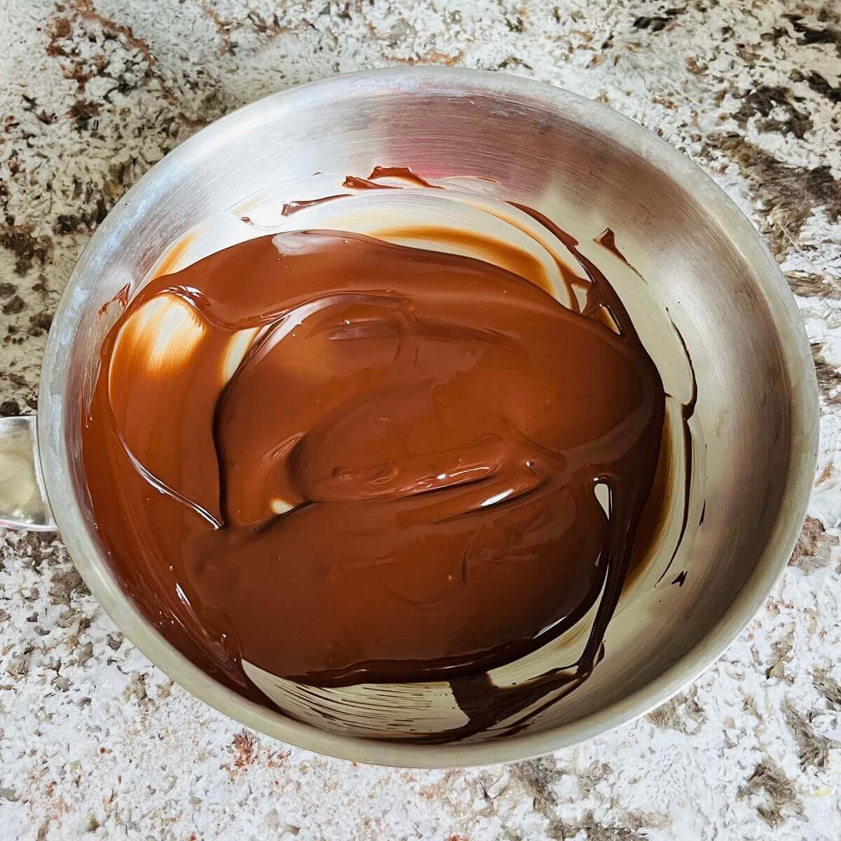 Melted dark chocolate in a steel pan.
