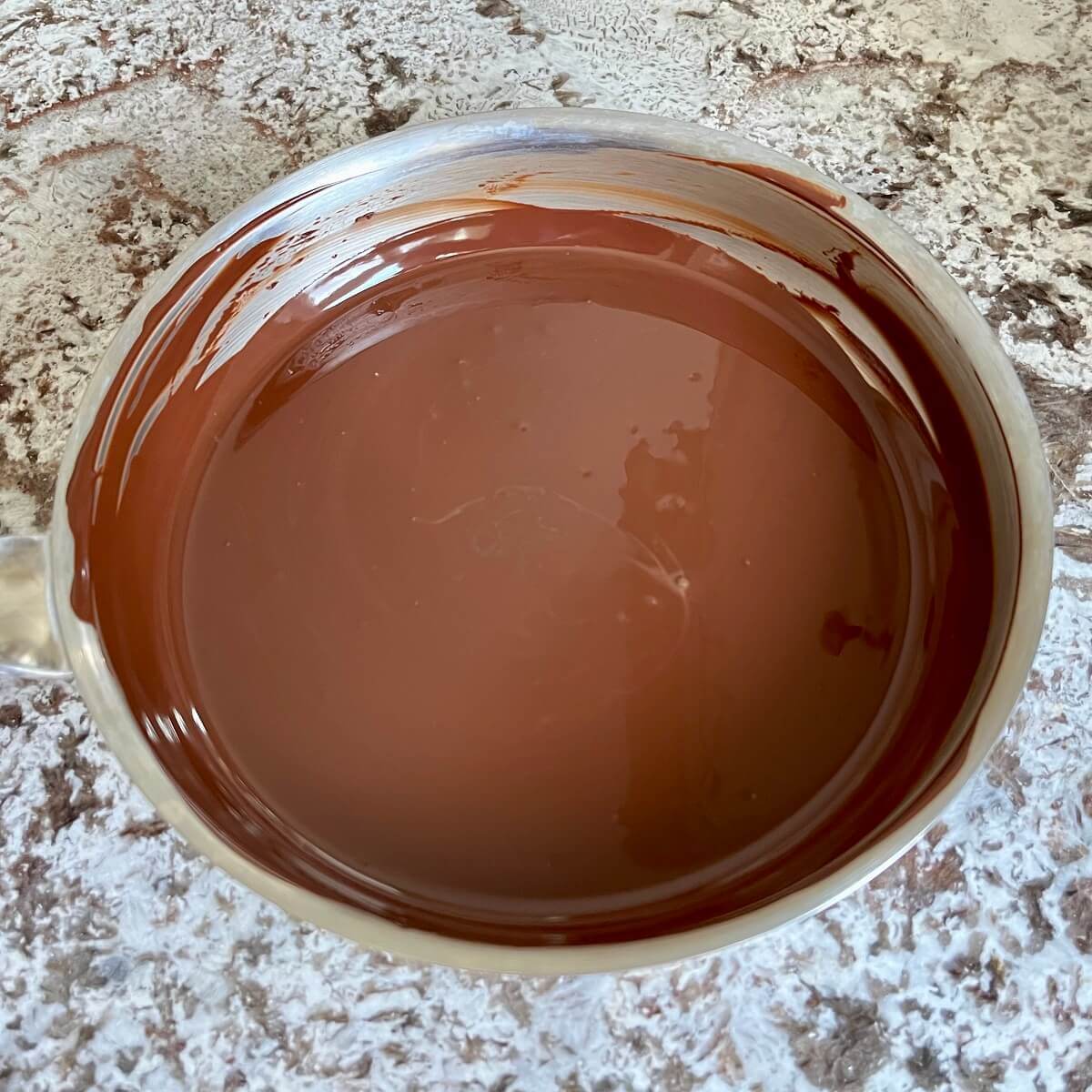 Hot melted dark chocolate in a steel pan.