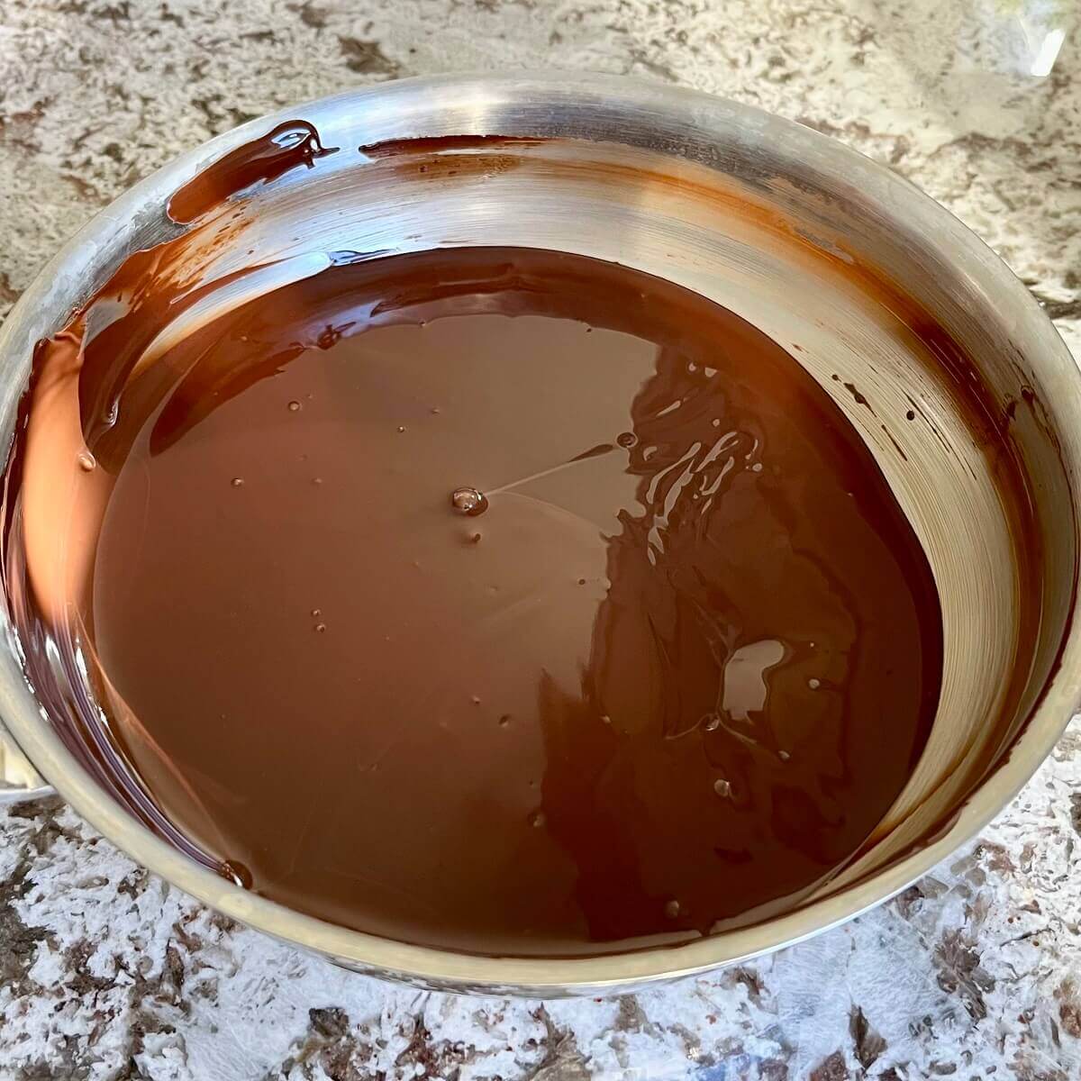A steel pan of melted dark chocolate.