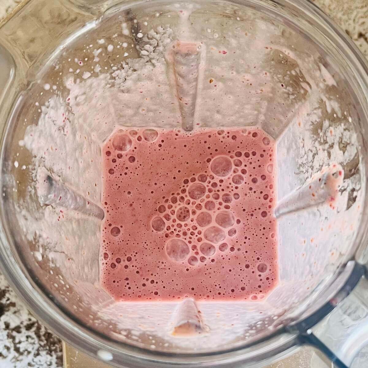 A creamy pink smoothie in a blender.