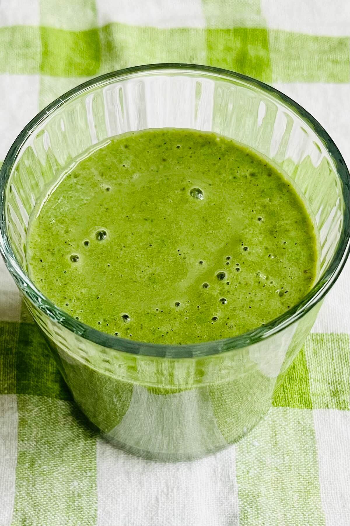 A green creamy smoothie in a glass.