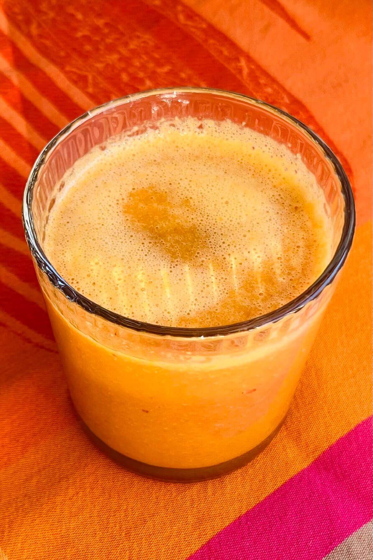 A smoothie made with carrot juice in a glass.