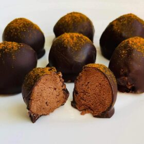 Sweet potato truffles sprinkled with turmeric on a white plate.