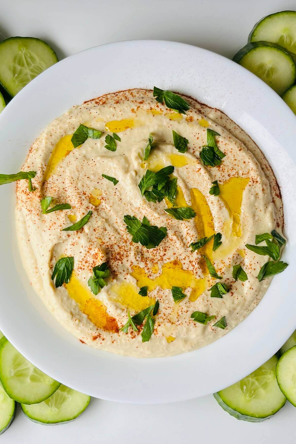 Hummus in a bowl sprinkled with fresh herbs and spices.