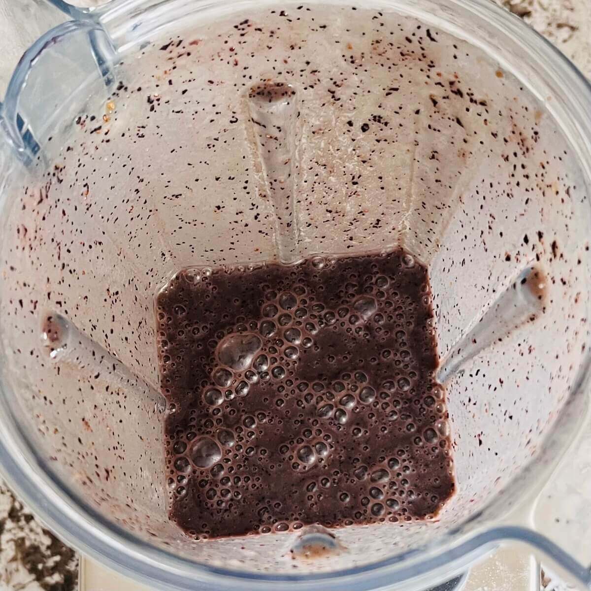 A dark purple smoothie in a blender.