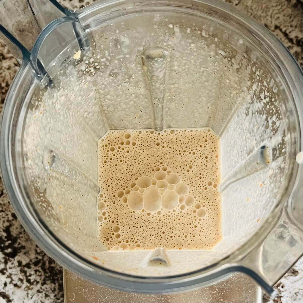 A creamy beige smoothie in a blender.