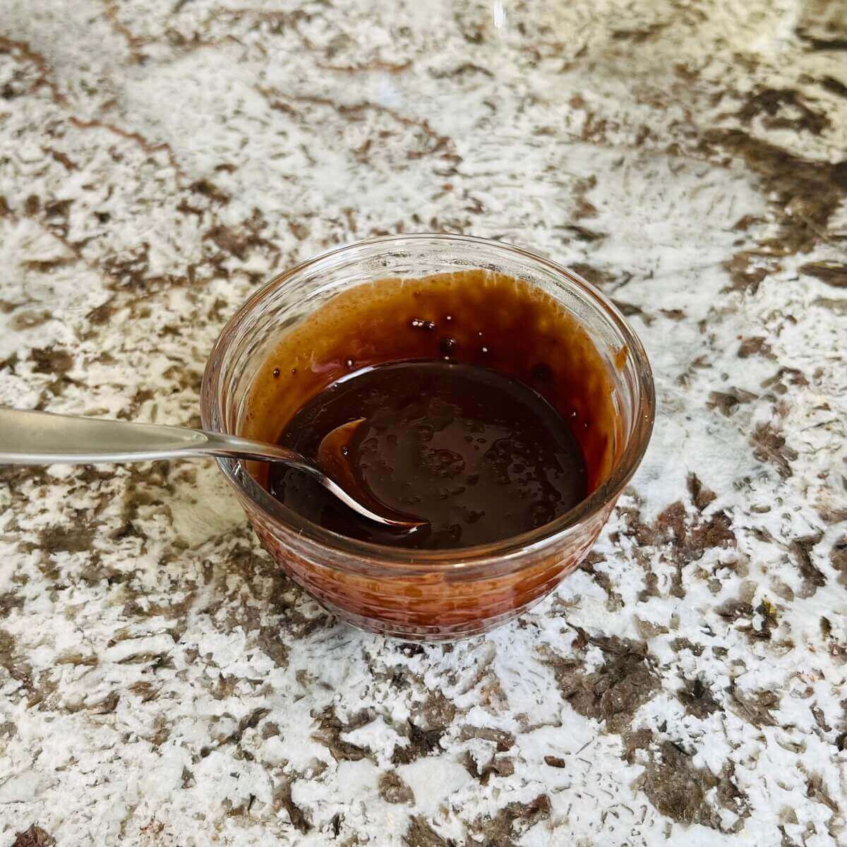 A liquid mixture of cocoa powder, coconut sugar, and water in a glass bowl.