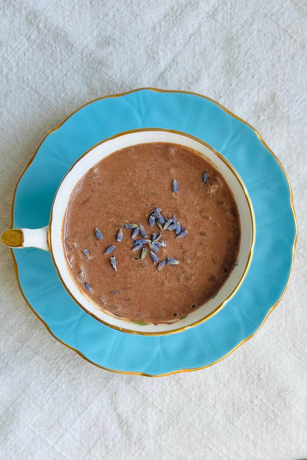 Hot chocolate sprinkled with dried lavender flowers in a teacup.