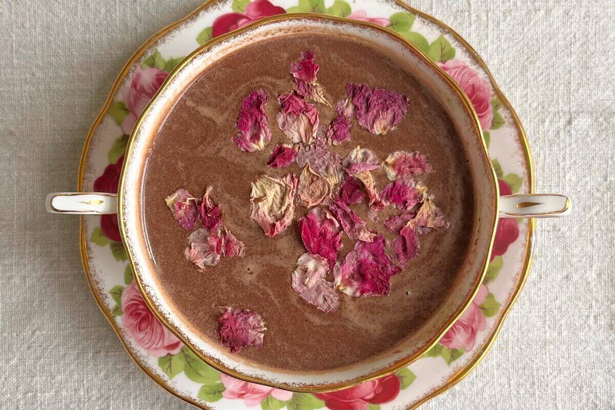 Hot cocoa in a teacup sprinkled with dried rose petals.