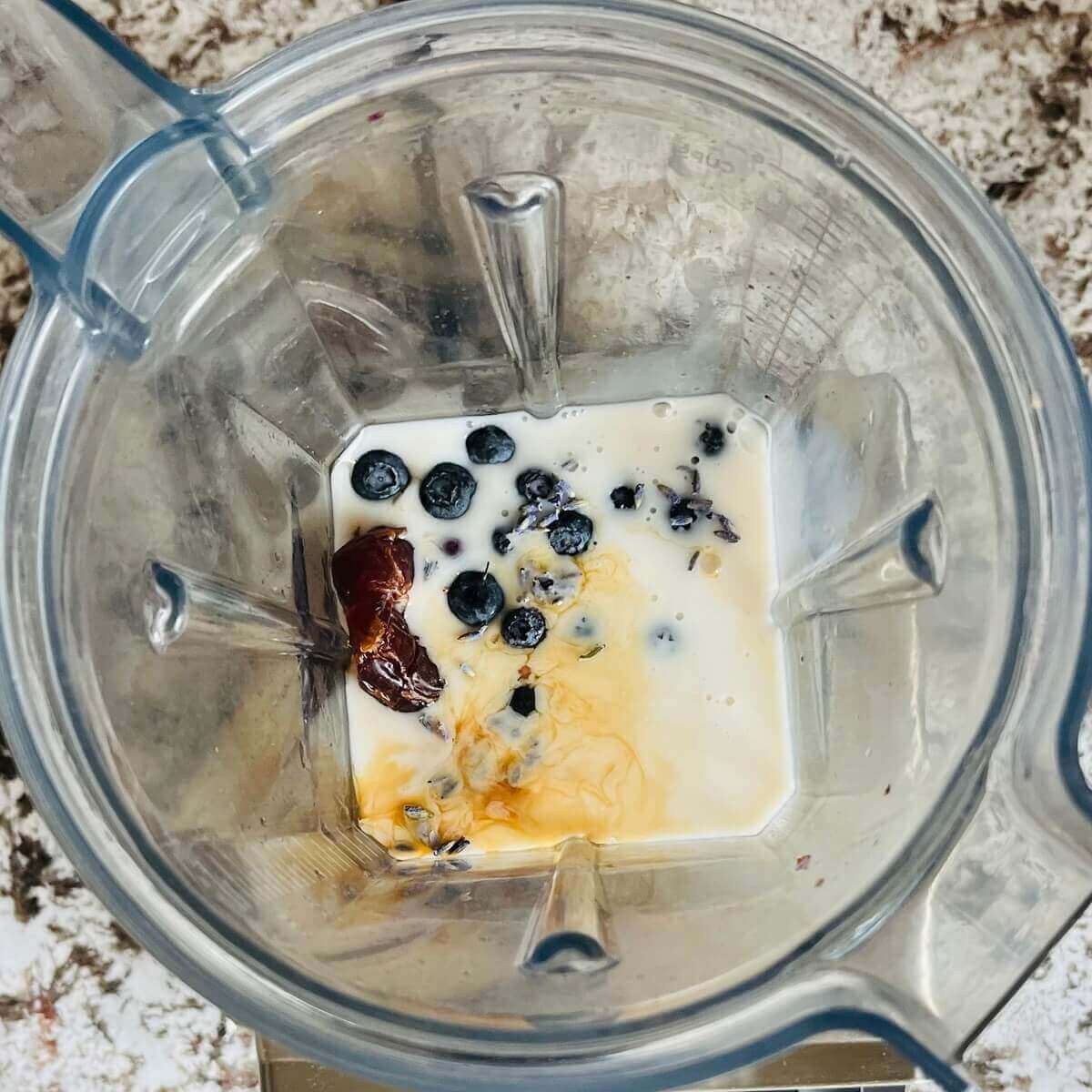 Dried lavender flowers, blueberries, a date, vanilla, and almond milk in a blender.