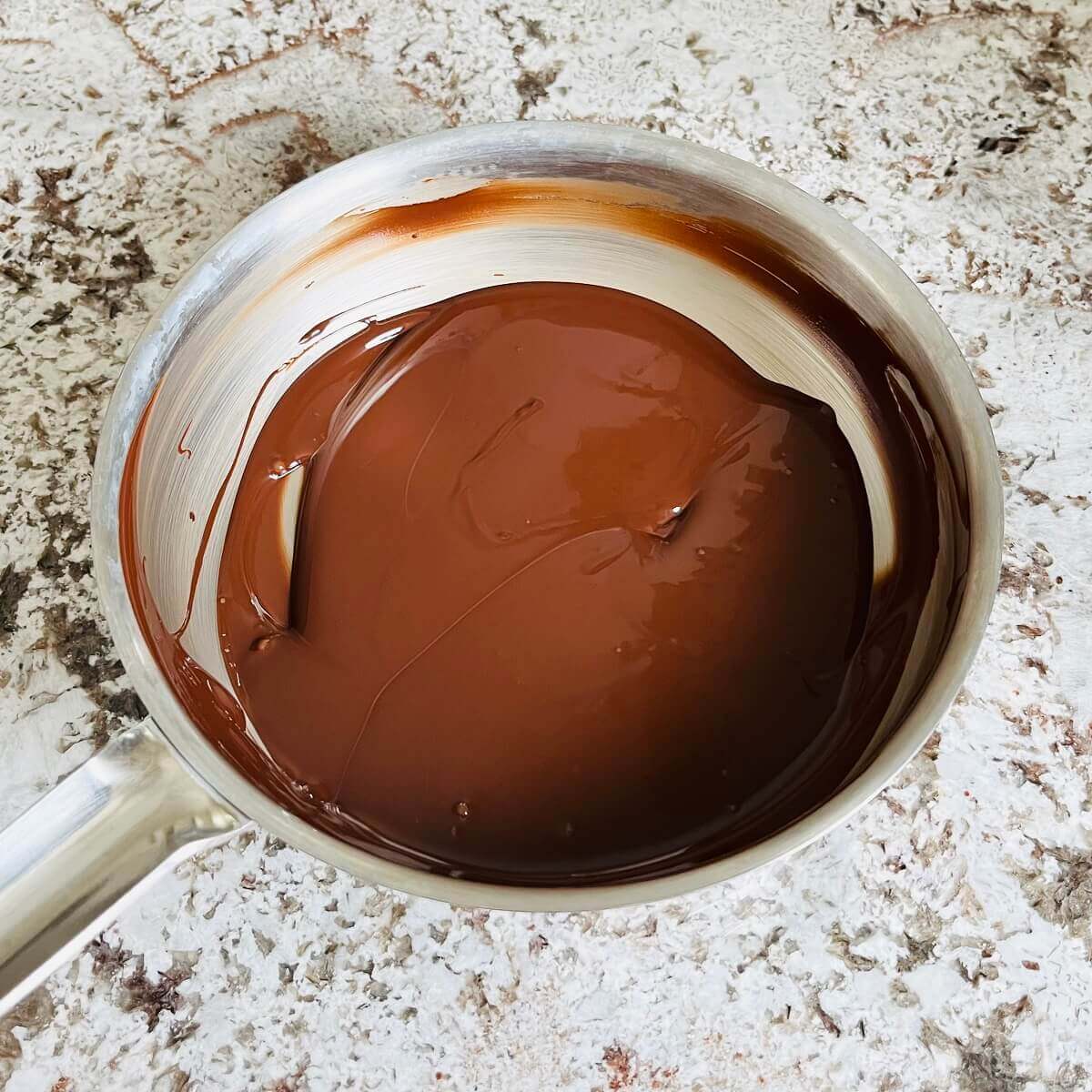 Melted dark chocolate in a steel pan.
