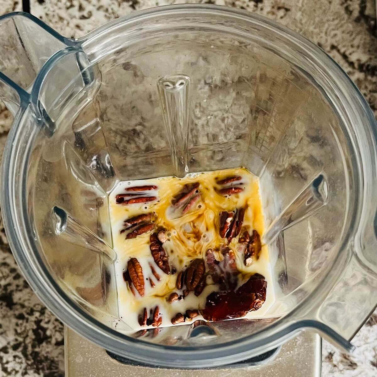 Pecans and other ingredients for a smoothie in a blender.