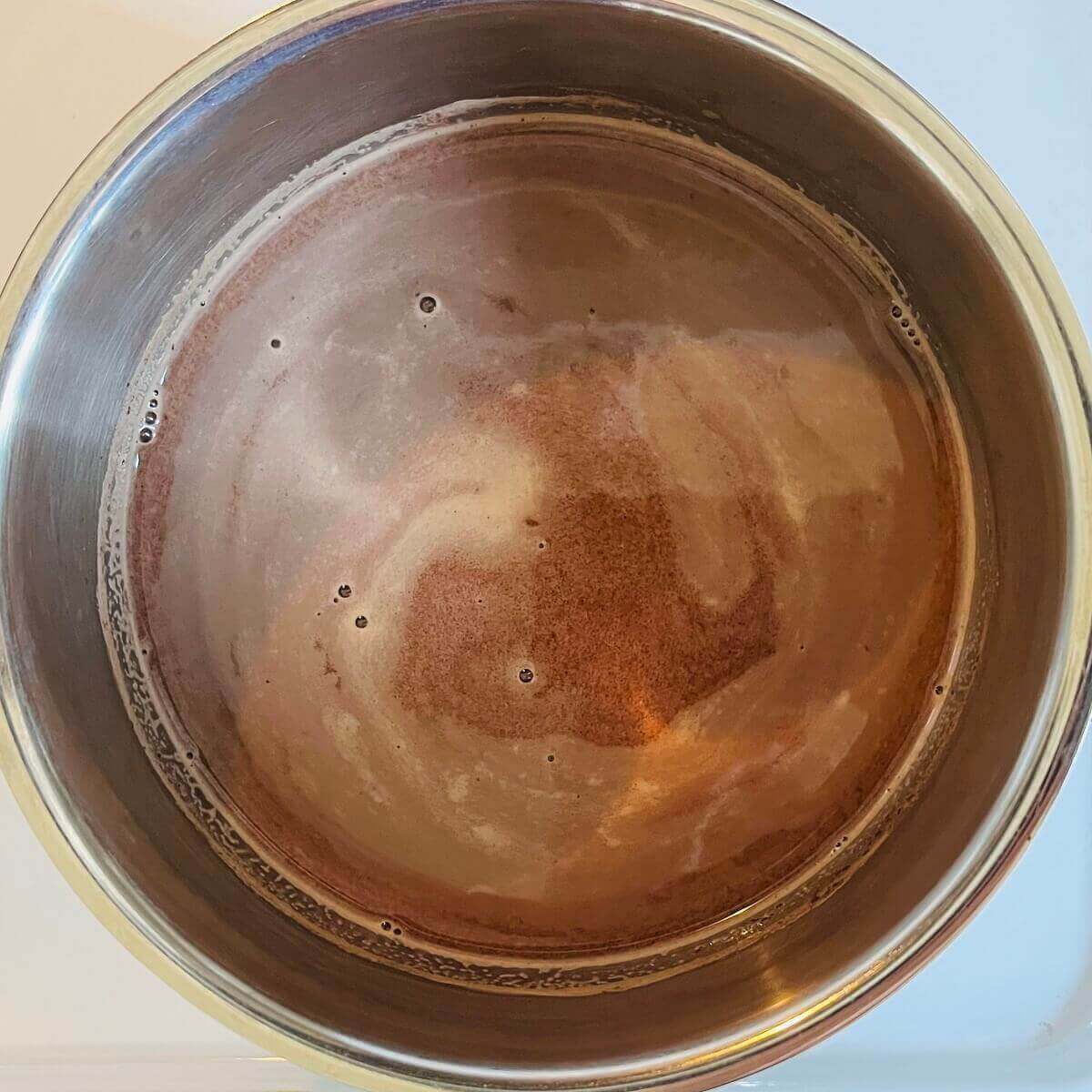 Rose water hot chocolate in a steel pot.