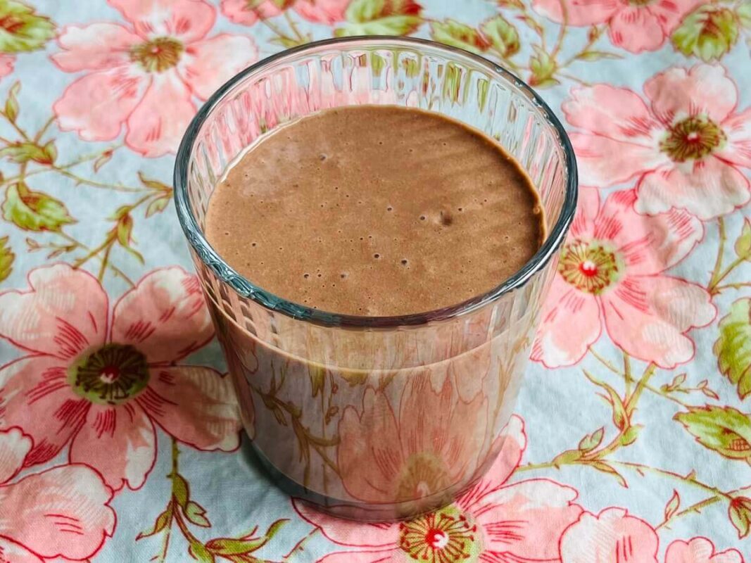 A smoothie in a glass on a floral placemat.