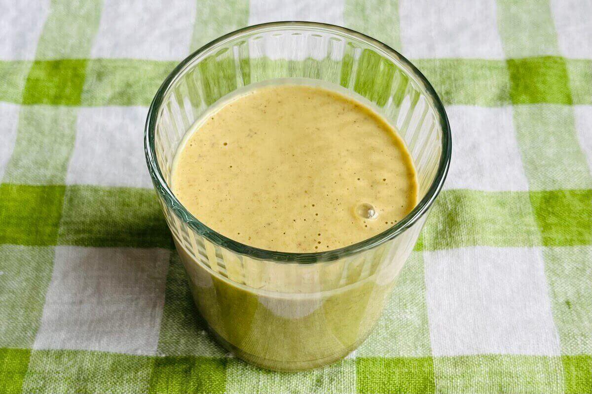 A smoothie made with pistachios on a green gingham cloth.