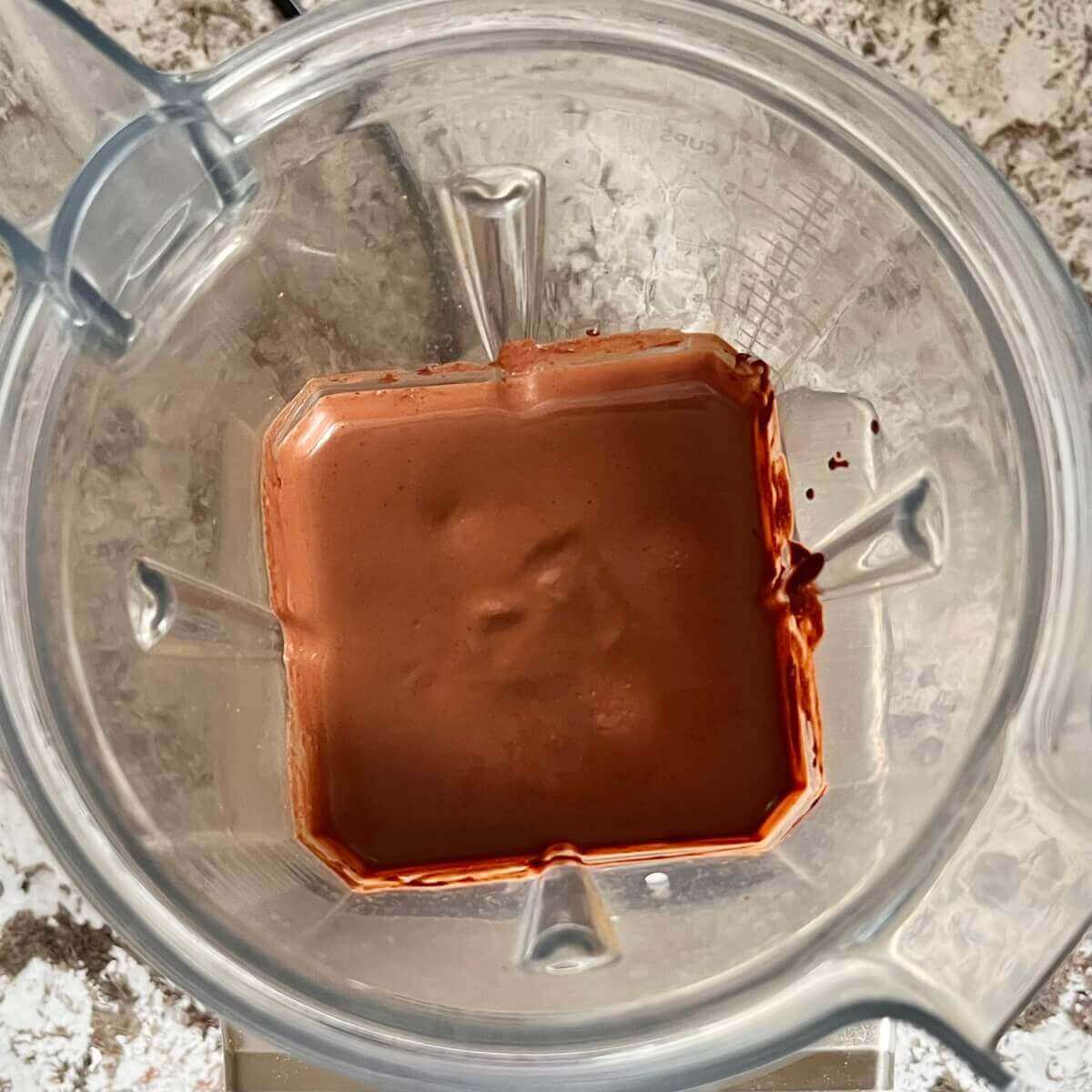 A creamy mixture of dark chocolate, hazelnuts, almond milk, and vanilla blended in a blender.