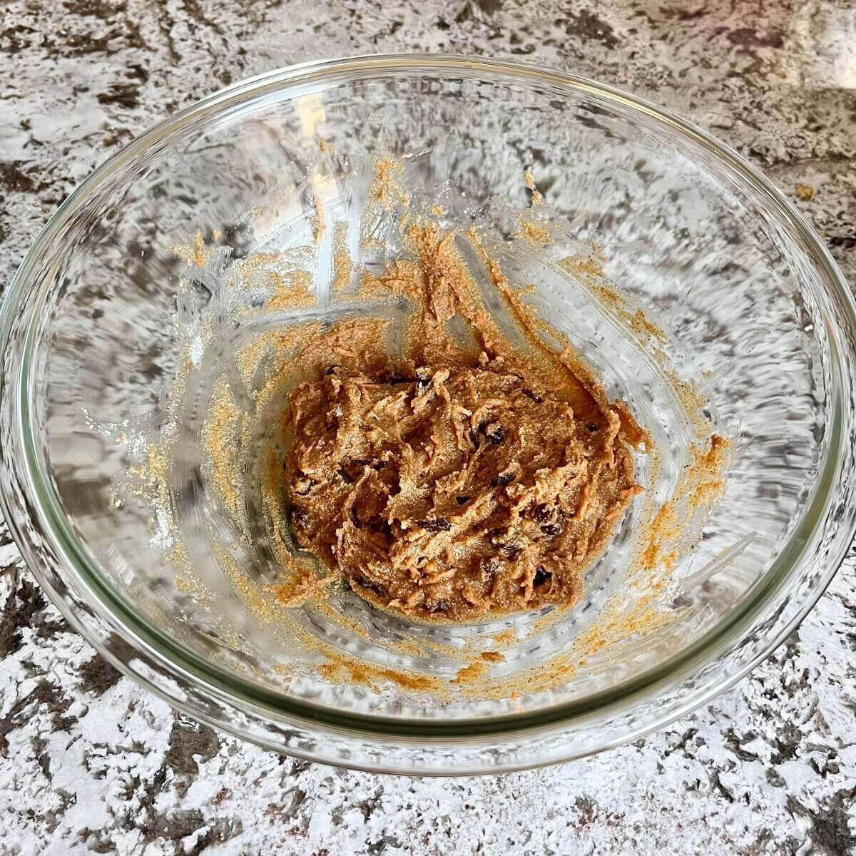Carrot cake cookie dough in a glass mixing bowl.