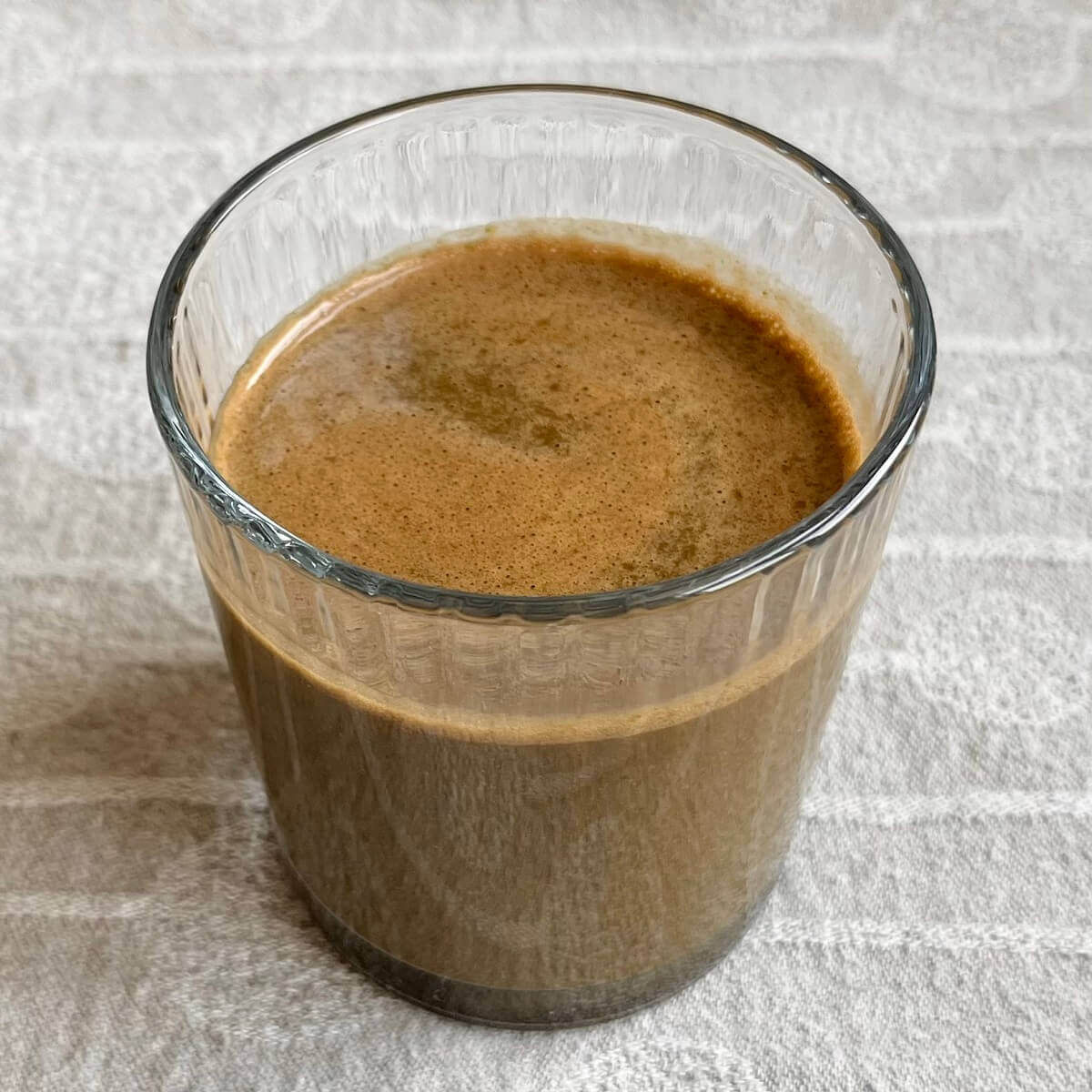 A chocolate spinach smoothie in a glass.