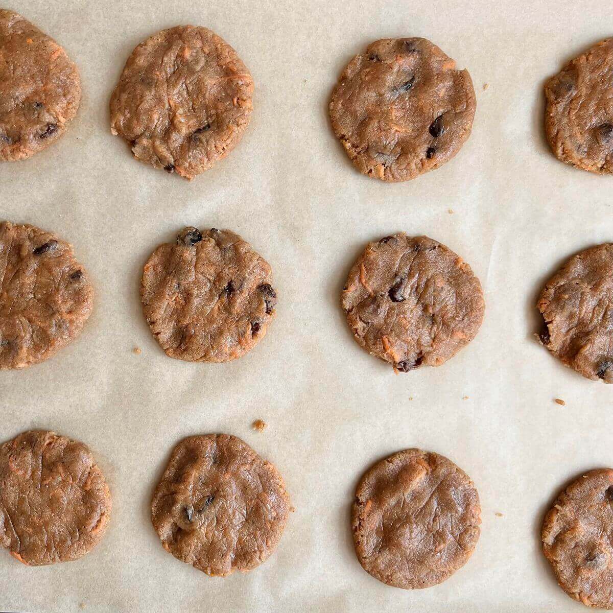 Raw carrot cookies on a baking sheet lined with parchment paper.