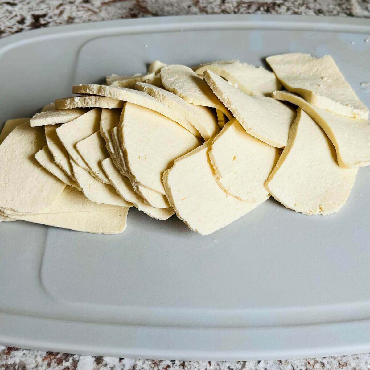 Thinly sliced tofu on a gray cutting board.