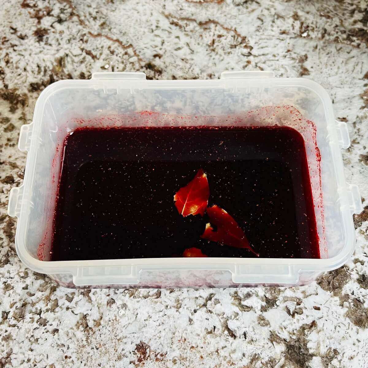 A dark pink marinade in a plastic container.