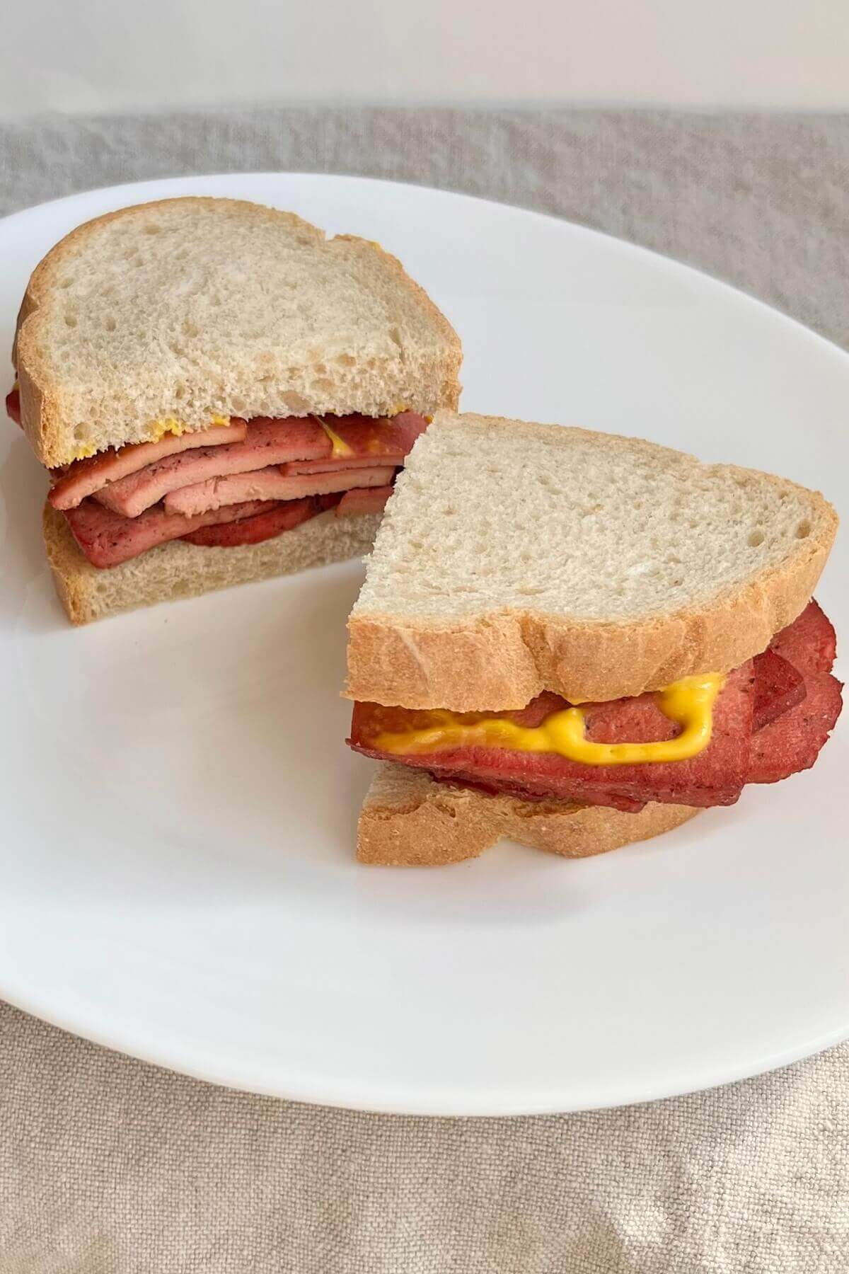 A vegan corned beef sandwich drizzled with mustard.