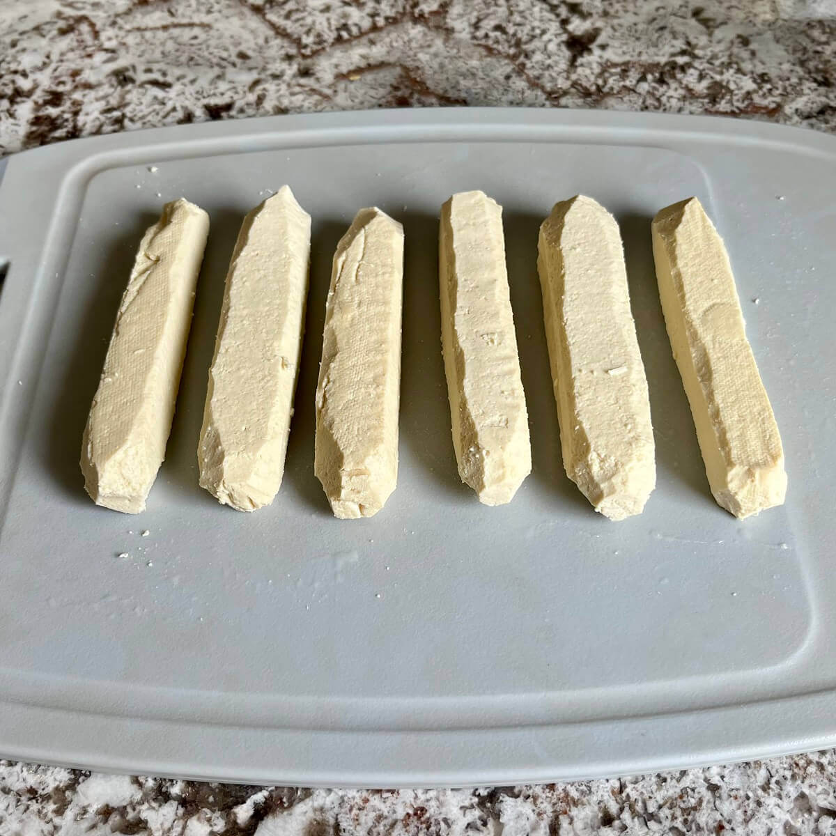 Six pieces of tofu shaped like hot dogs.